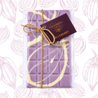 Purple chocolate bar with white drizzle and a visible brand tag on a patterned background