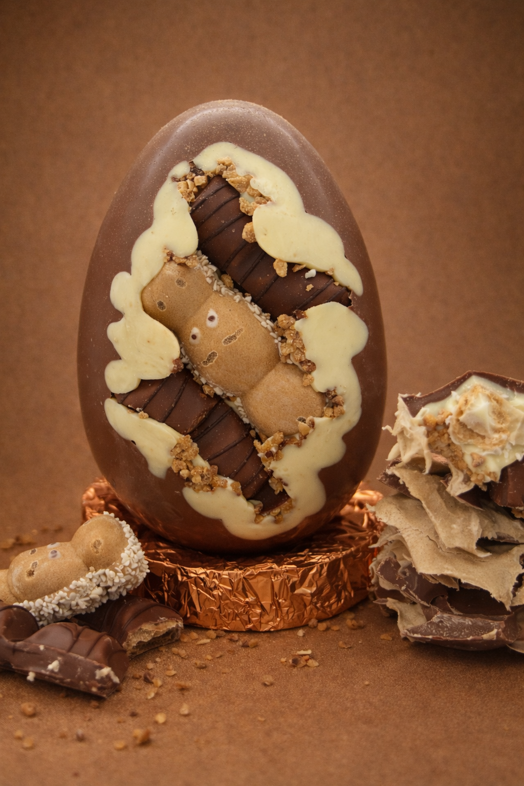 Decorative chocolate egg with white and brown toppings on a brown background